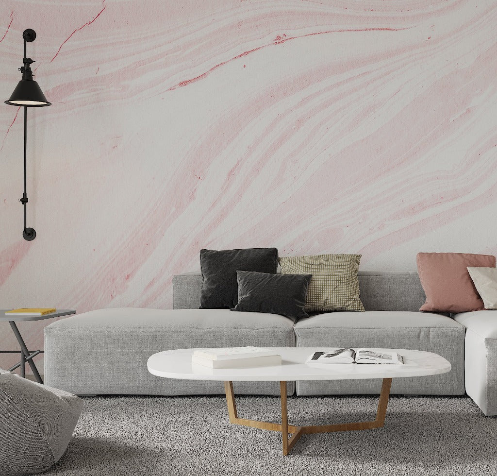 Living Room - A modern living room with a gray sofa adorned with various cushions, a round white coffee table with books on it, a hanging black lamp, and a Decor2Go Wallpaper Mural Pink Marble Wallpaper Mural background.