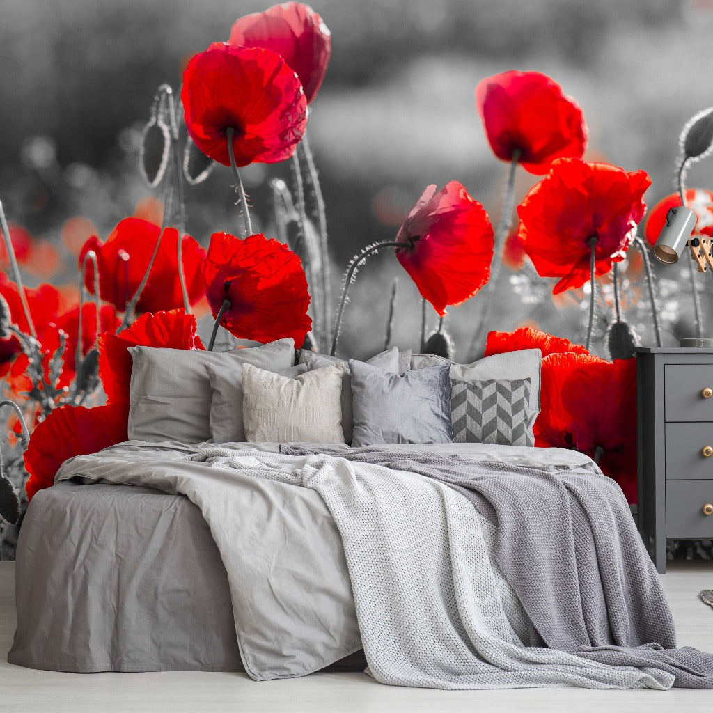 A stylish bedroom featuring a bed adorned with a gray duvet and patterned pillows, adjacent to a gray dresser. The background boasts the Decor2Go Wallpaper Mural, depicting a vivid field of oversized Poppy Dancing.