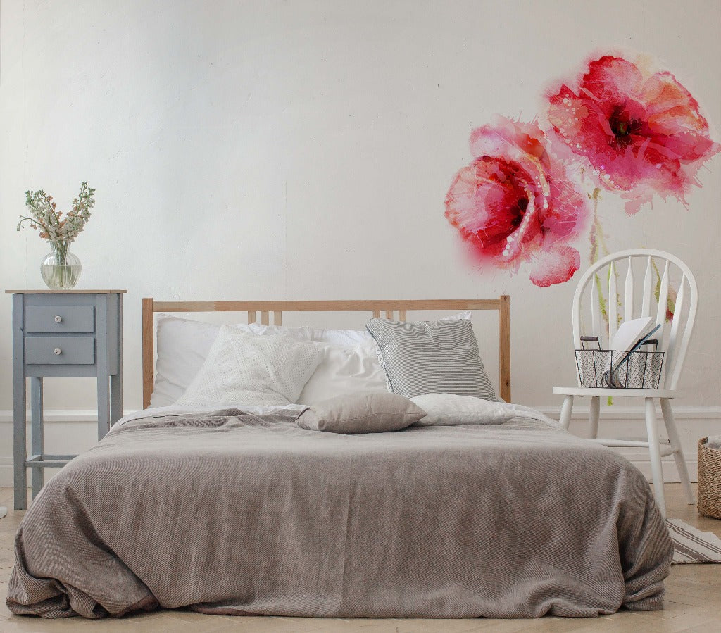 A serene bedroom with a neatly made bed covered with a gray duvet, flanked by a nightstand and a white chair, with the Red Poppies Watercolor Wallpaper Mural on the wall by Decor2Go Wallpaper Mural.