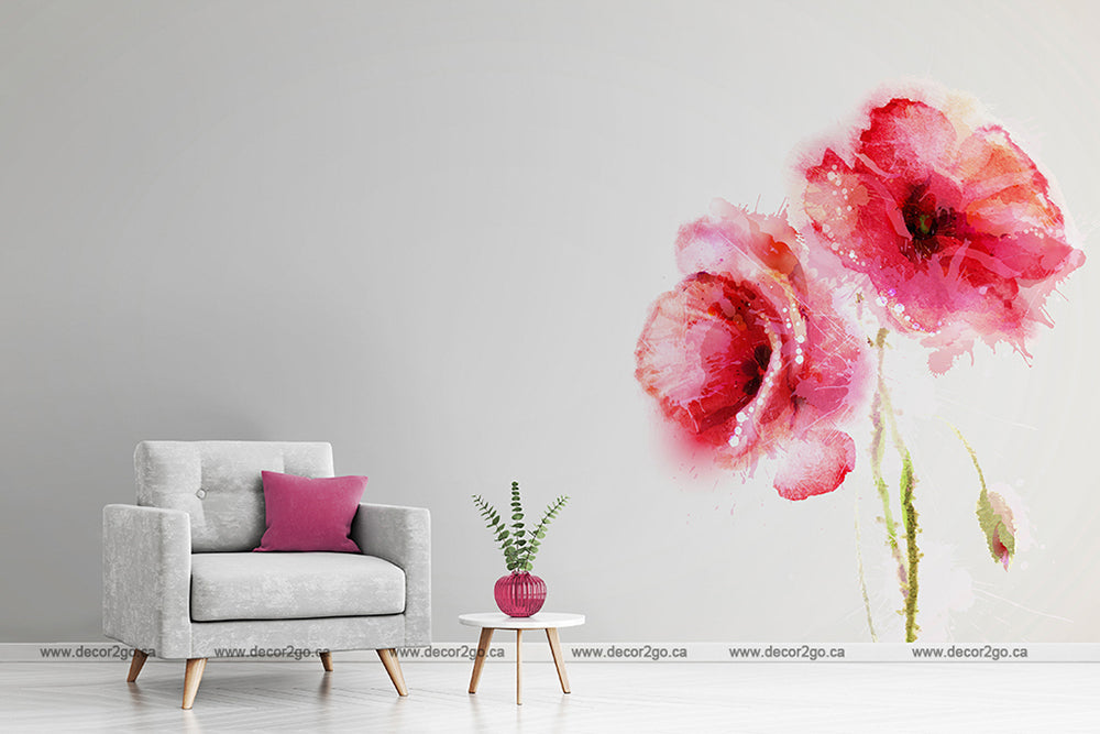 A minimalistic room featuring a light gray armchair with a pink cushion, a small round table with a potted plant, and Decor2Go Wallpaper Mural depicting Red Poppies Watercolor on a white wall.
