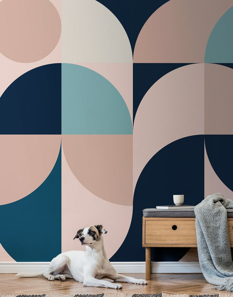 A dog lying on a rug against a backdrop of a Decor2Go Wallpaper Mural in shades of navy, teal, and peach. Next to the dog is a small wooden nightstand with a cup and a.