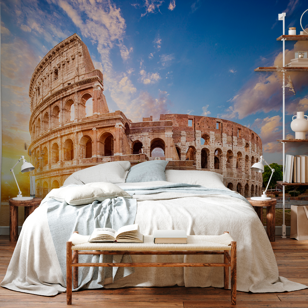 A surreal bedroom with a large bed and an open book on it, blending into a scenic backdrop of the Decor2Go Wallpaper Mural Roman Colosseum Wallpaper Mural under a blue sky with light clouds.