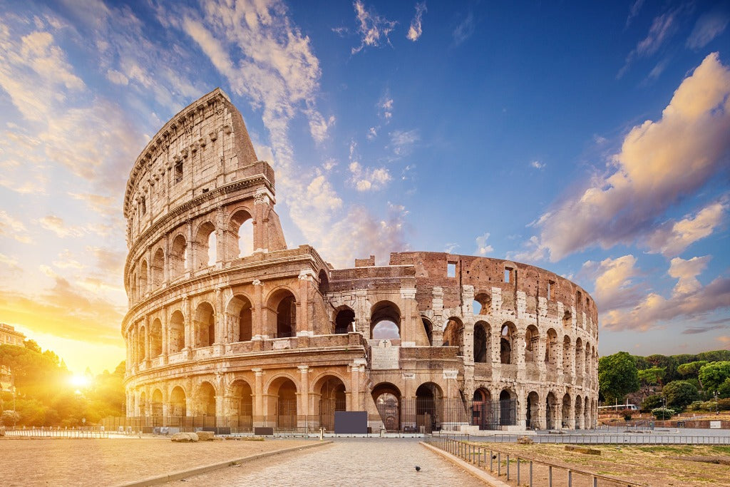 The Decor2Go Wallpaper Mural at sunset, showcasing its massive, ancient structure with sun rays filtering through arches against a blue sky with soft clouds.