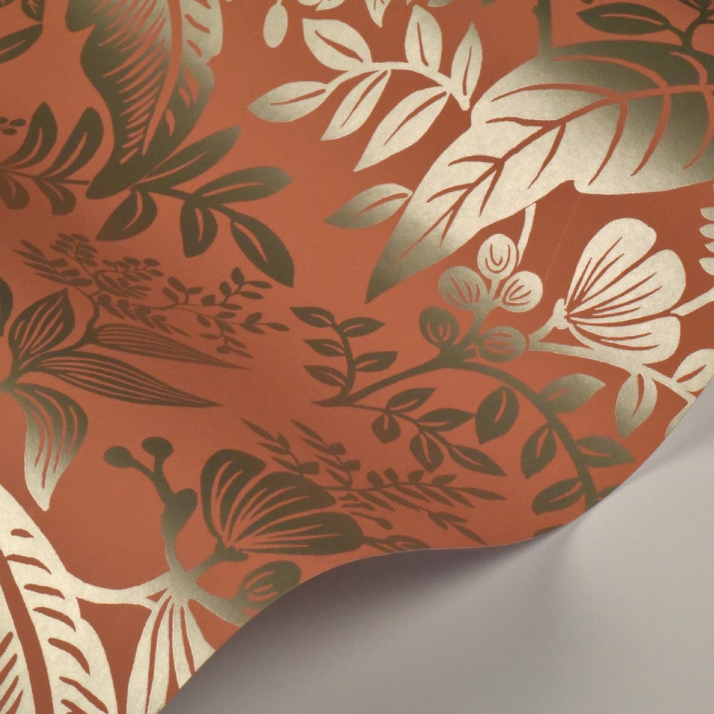 A sheet of Rose Canopy Wallpaper (60 SqFt) by York Wallcoverings features orange with metallic gold floral and leaf patterns. The wallpaper is slightly curled at the edge, showing its plain underside.