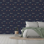 Bedroom - A modern bedroom featuring a white bed with gray and green bedding, a small potted plant on stacked books beside it, and a dark blue Decor2Go Wallpaper Mural with colorful boomerang.