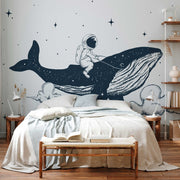 Bedroom - A whimsical children's bedroom with a large Decor2Go Wallpaper Mural featuring an astronaut riding a whale in space, embodying a dream-like aesthetic. The room includes a neatly made bed, wooden bench, and floating