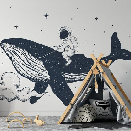 A children's room with a Space Whale Wallpaper Mural from Decor2Go Wallpaper Mural depicting an astronaut riding a whale among stars. Features include a wooden dresser, a teepee, toys, and a neutral color palette.