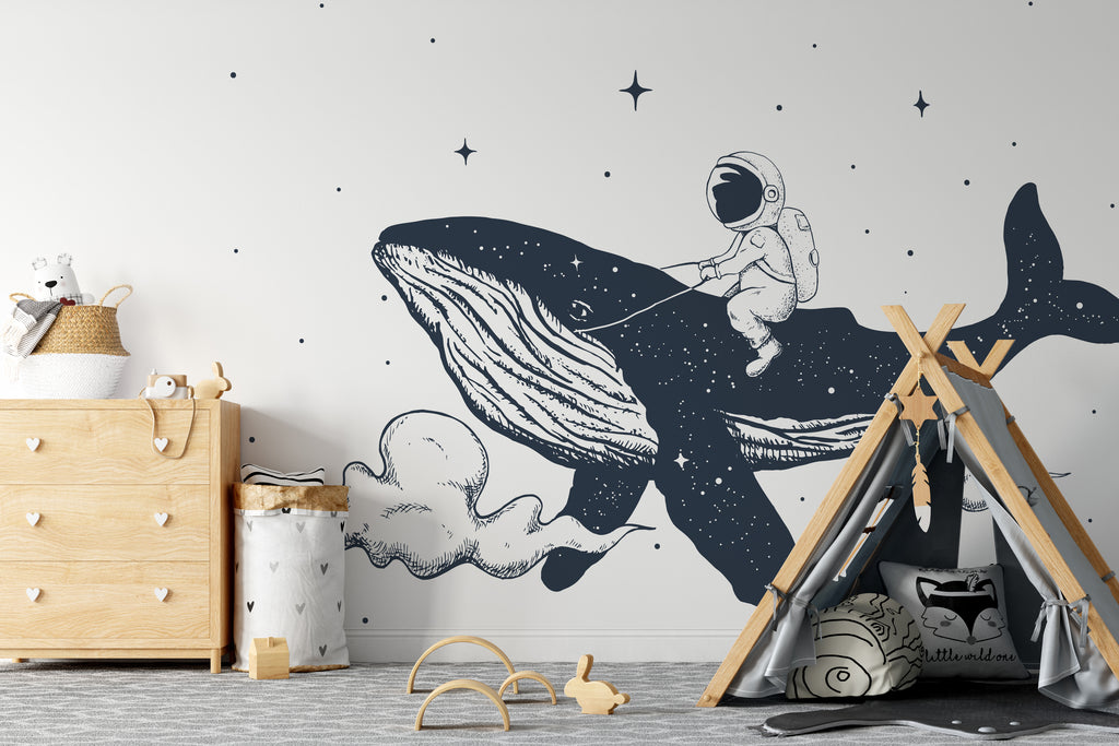 A children's room with a Space Whale Wallpaper Mural from Decor2Go Wallpaper Mural depicting an astronaut riding a whale among stars. Features include a wooden dresser, a teepee, toys, and a neutral color palette.