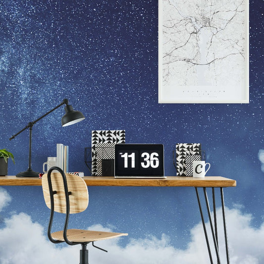 A modern home office setup with a wooden desk, black metal legs, and a Decor2Go Wallpaper Mural backdrop. The desk holds a laptop, desk lamp, decorative books, and a digital clock.