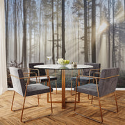 A modern dining area showcases a round glass table with four gray chairs, enhanced by Decor2Go's Sun Rays Through the Forest Wallpaper Mural. Sunlight filters through trees, illuminating a wine glass and a flower vase on herringbone wood flooring.