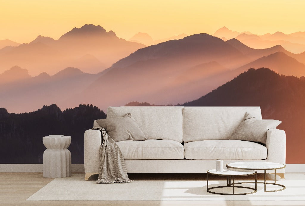 Living Room - A modern living room setup with a beige sofa, small tables, and a rug, overlooking a tranquil Sunset on the Mountains Wallpaper Mural bathed in the warm glow of a sunset from Decor2Go Wallpaper Mural.