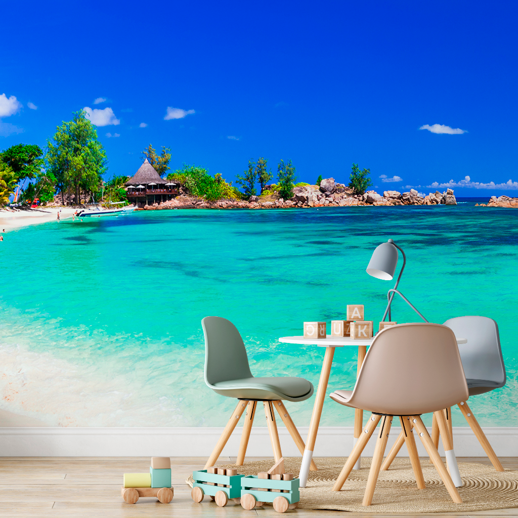 Office furniture including a desk and chairs, with educational children’s blocks, against a Decor2Go Wallpaper Mural of a beach with clear blue water and a sunny sky.