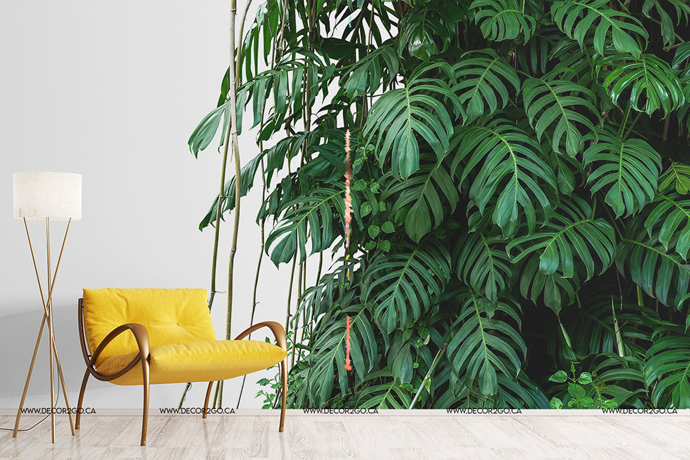 Living Room - A modern living room corner with a large, lush green wall of Tropical Jungle Leaves Wallpaper Mural from Decor2Go Wallpaper Mural. A minimalist yellow armchair and a white floor lamp are to the left, enhancing the serene indoor garden vibe.