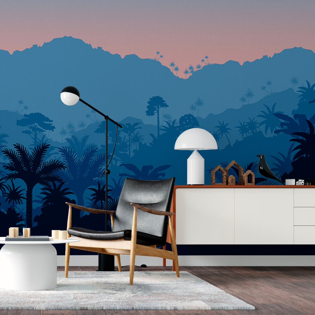 A stylish living room with a Decor2Go Wallpaper Mural showing silhouetted mountains and palm trees. Modern furniture includes a wooden chair with a black cushion, a white lamp, and a sideboard.