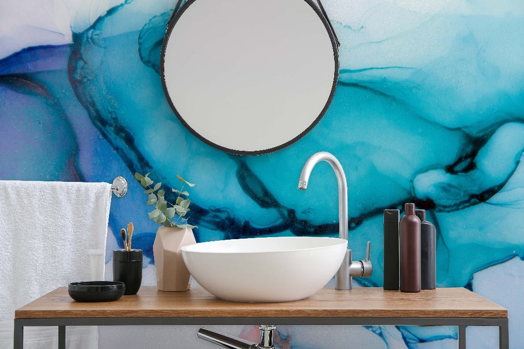 Bathroom - Modern bathroom vanity with a circular mirror and a vessel sink set against a Decor2Go Wallpaper Mural. Accessories include dark bottles and a plant.