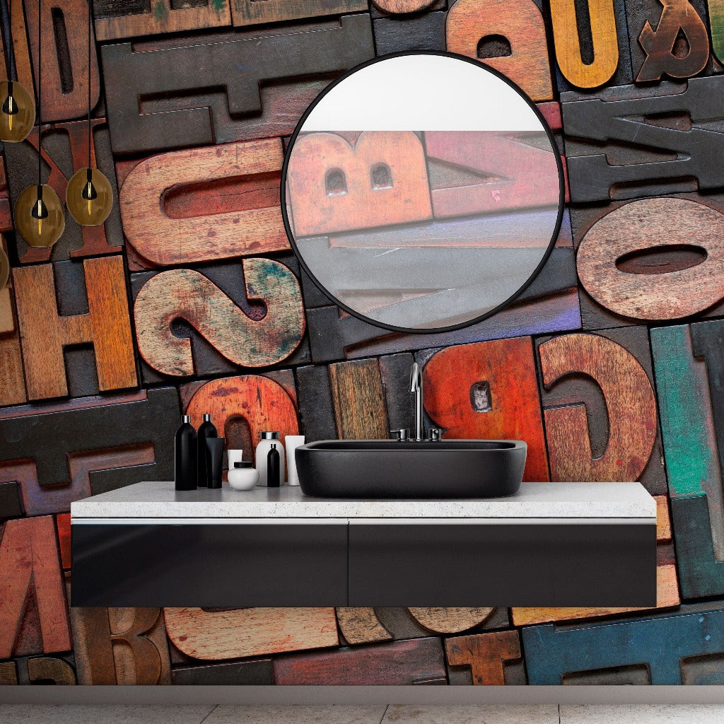 A modern bathroom vanity against a colorful wall with a Decor2Go Wallpaper Mural. A round mirror reflects a blurred image, with hanging pendant lights and toiletries on the countertop.