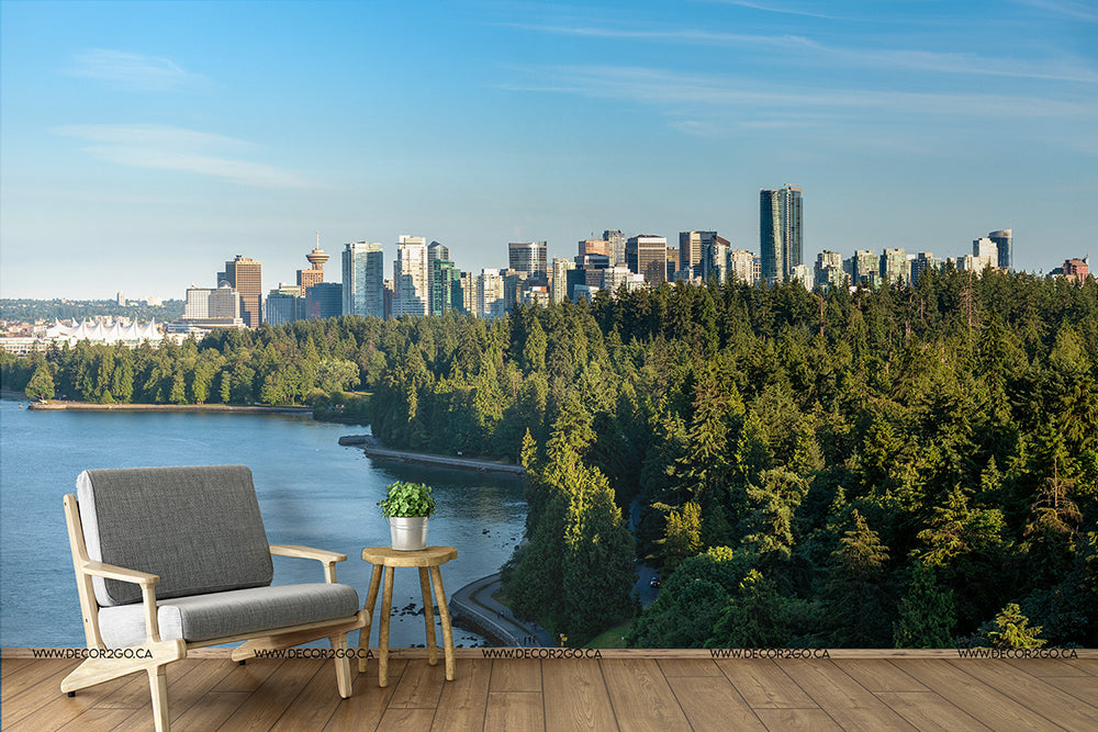 A serene balcony view overlooking a vibrant cityscape next to a lush green park, featuring a modern armchair and side table set against a backdrop of Decor2Go Wallpaper Mural's Vancouver Summer Skyline Wallpaper Mural and clear blue skies.