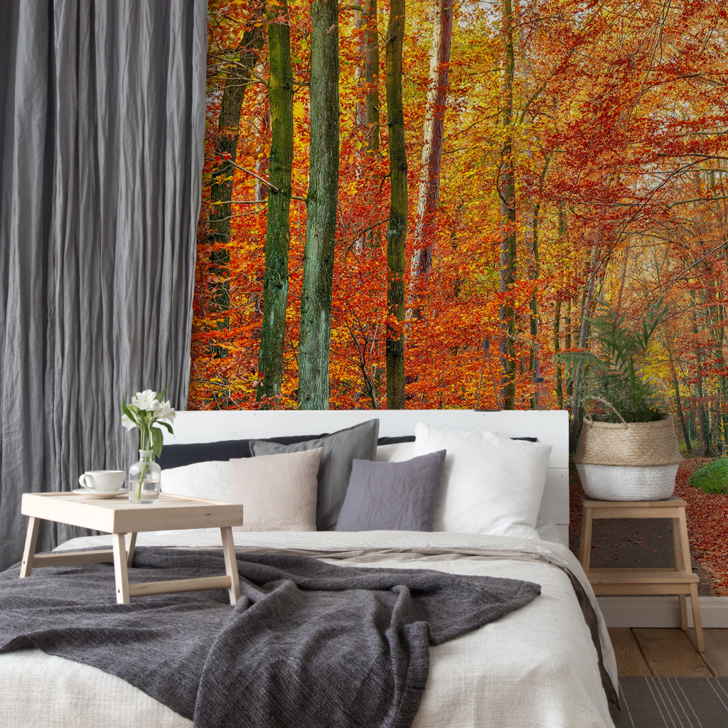 A cozy bedroom with a large bed covered in white linens and a gray blanket, facing a floor-to-ceiling window showcasing a Decor2Go Wallpaper Mural with red and orange foliage.