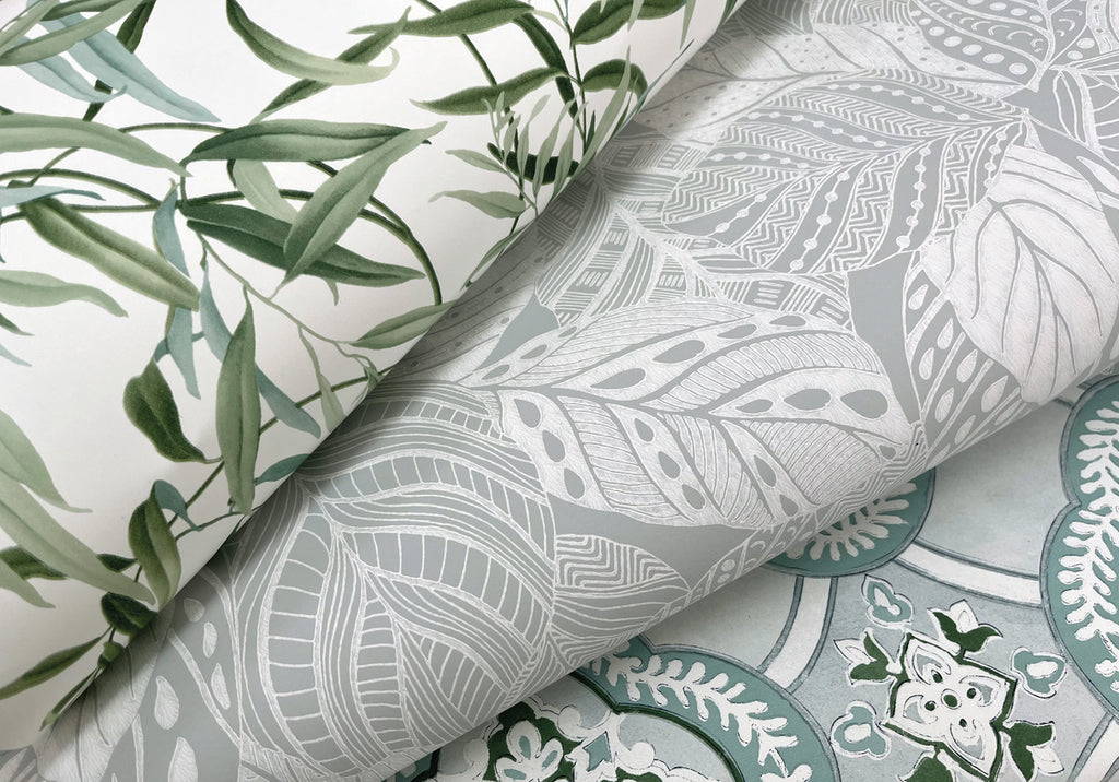 Rolls of Vinca Eucalyptus Wallpaper Green (60 Sq.Ft.) with various designs, including a leaf pattern in green and white, and a monochrome botanical print by York Wallcoverings.