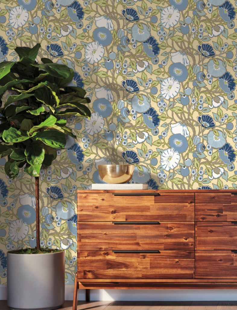 yellow blue floral wallpaper on the wall, wooden dresser in front of the wall and big green plant