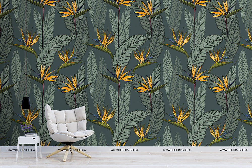 A modern room features a chair with thin metal legs and a soft beige cushion against a wall adorned with Decor2Go Wallpaper Mural's Vintage Botanical Garden Wallpaper Mural. The wallpaper is decorated with yellow and orange flowers and green leaves. The wooden floor complements the design, while a potted plant adds a touch of freshness on the left.