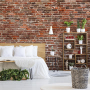 Bedroom - A cozy, rustic bedroom with Decor2Go Wallpaper Mural's Washed Classic Brick Wall Wallpaper Mural, featuring a bed with white linens, a wooden headboard, and a book on the bed. A shelving unit displays plants and decor.
