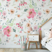 Bedroom - A cozy children's bedroom with a Watercolor Pink Flowers Wallpaper Mural from Decor2Go Wallpaper Mural featuring large pink blossoms, a white bed shaped like a house, and a white nightstand with a pink lamp.