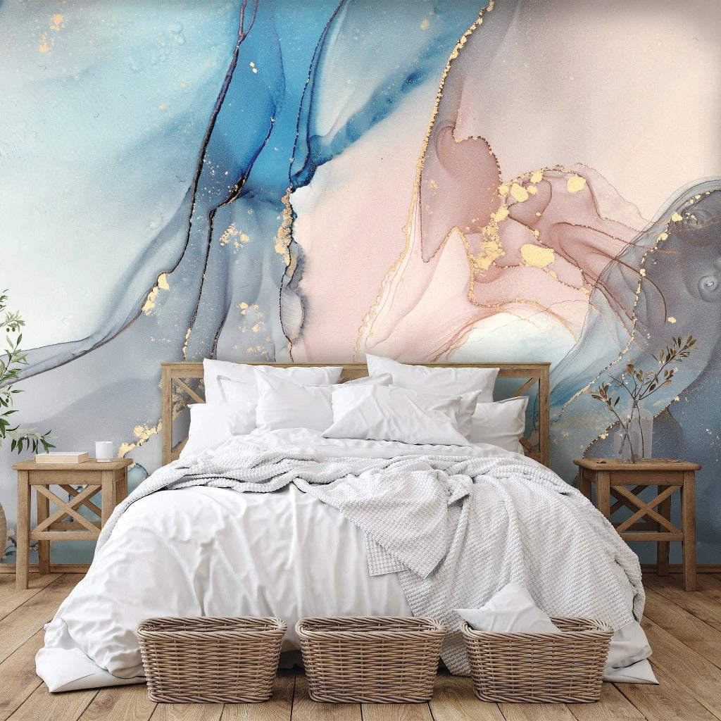 A cozy bedroom featuring an unmade bed with white bedding, flanked by wooden side tables and wicker baskets, against a Decor2Go Wallpaper Mural backdrop of swirling blues and golds.