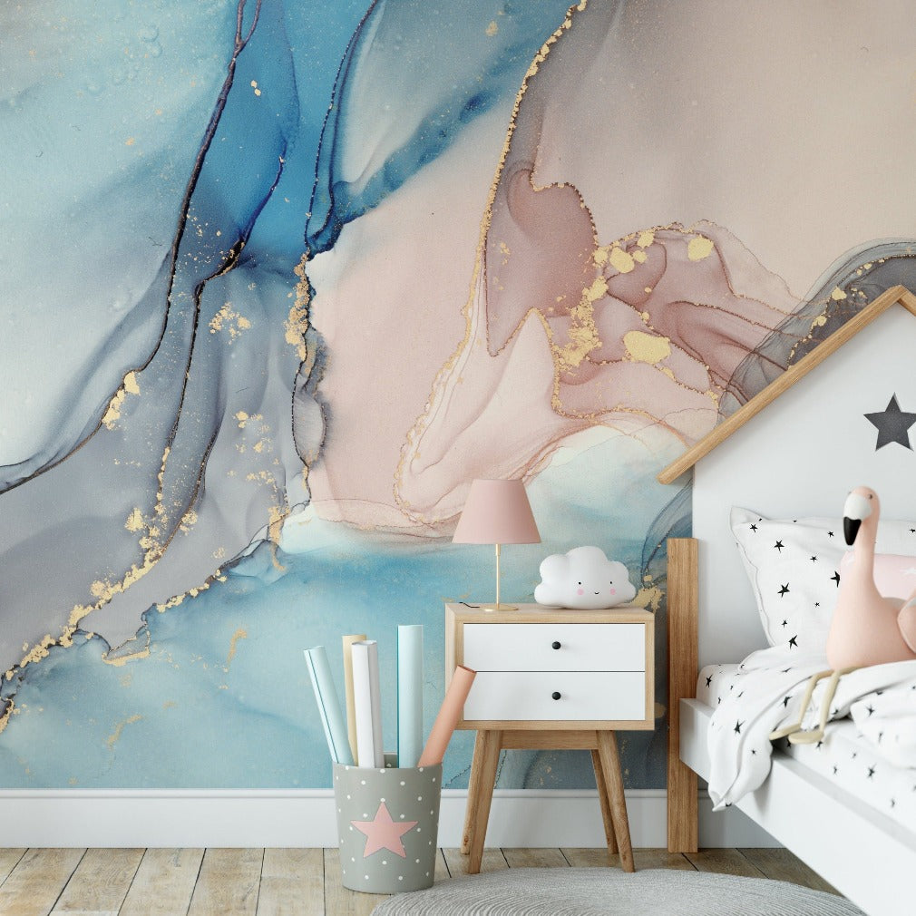 A stylish children's bedroom featuring a large wall covered with a Decor2Go Wallpaper Mural in tones of blue and pink, complemented by gold accents. A white bed with star-patterned bedding and a small