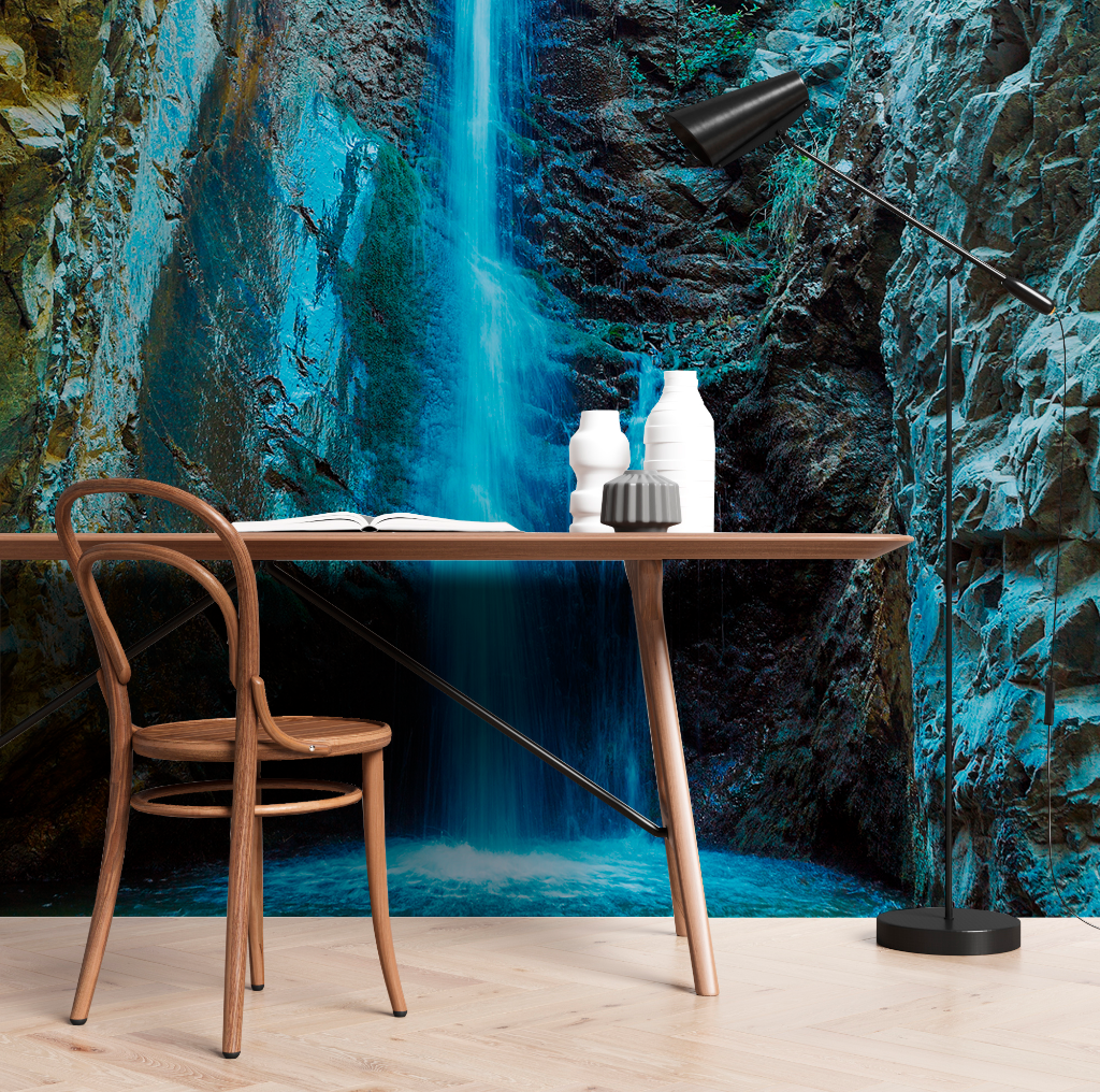 A modern study corner featuring a minimalist desk with a book, unique vases, and a bending floor lamp, set against vibrant Decor2Go Wallpaper Mural of a Waterfall Cave Wallpaper Mural in a rocky environment.