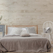 Bedroom - A cozy bedroom featuring a neatly made bed with gray bedding, a wooden headboard, a gray nightstand, and a white chair with a book against a Decor2Go Wallpaper Mural.