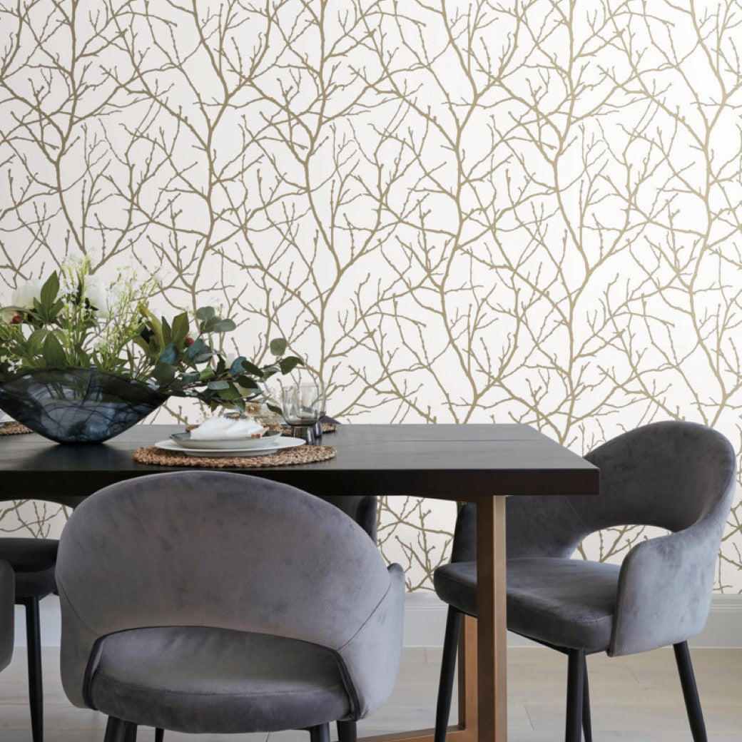 Dining Room - The area showcases a dark wooden table, gray velvet chairs, and a flower arrangement in a blue glass bowl. The room's elegance is enhanced by York Wallcoverings' White & Gold Trees Silhouette Wallpaper (57 SqFt), featuring a sophisticated tree pattern