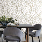 The dining area showcases a dark wooden table, gray velvet chairs, and a flower arrangement in a blue glass bowl. The room's elegance is enhanced by York Wallcoverings' White & Gold Trees Silhouette Wallpaper (57 SqFt), featuring a sophisticated tree pattern.