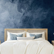 Bedroom - A modern bedroom featuring a bed with a decorative beige headboard and white bedding, complemented by blue and white pillows, against an Decor2Go Wallpaper Mural deep blue textured feature wall.