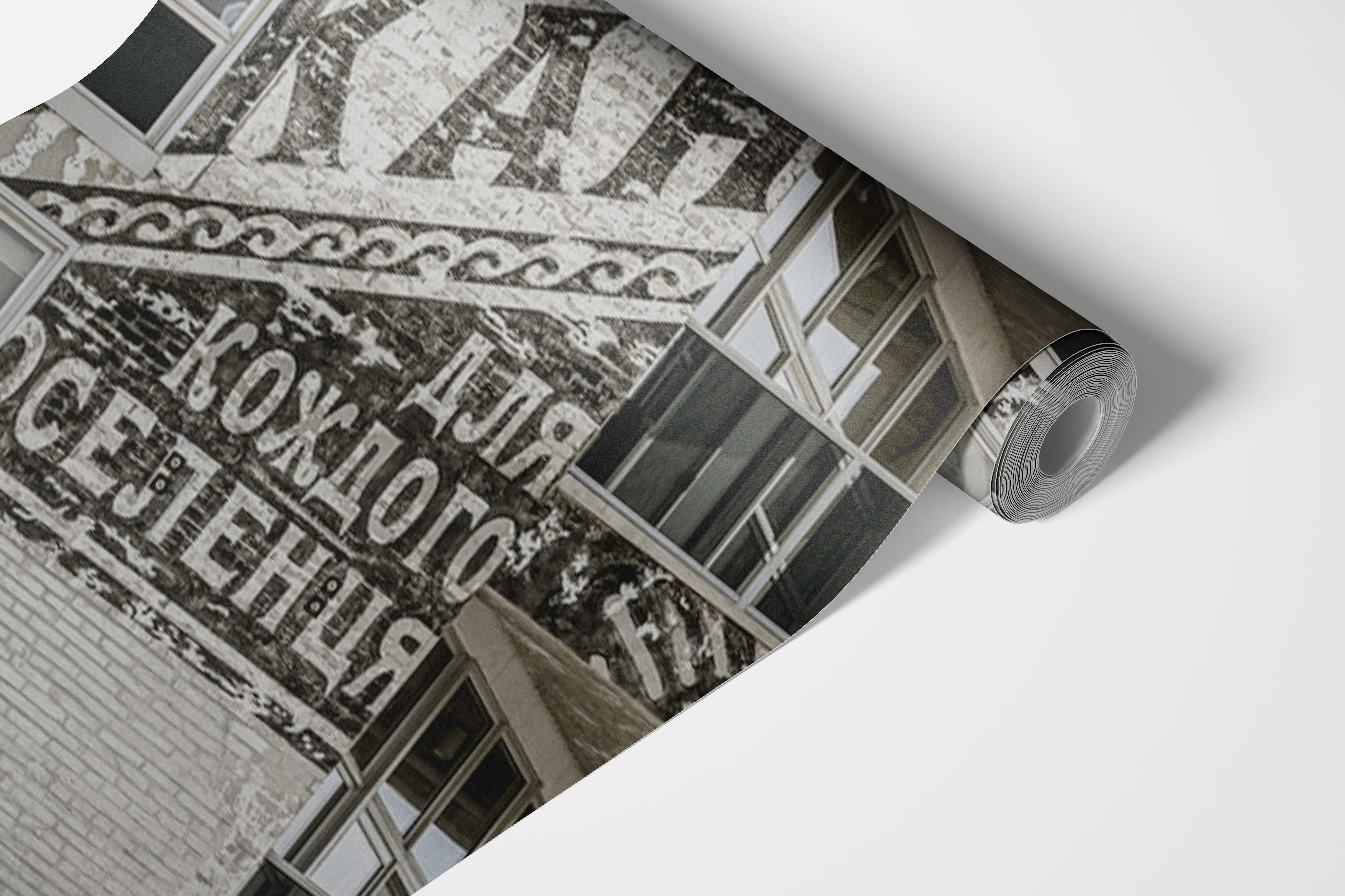 Roll of wallpaper with architectural design and text in a sepia tone.