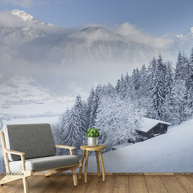 A tranquil Winter is Coming Wallpaper Mural scene with a modern chair and side table set on a balcony overlooking a snow-capped forest and mountains shrouded in mist by Decor2Go Wallpaper Mural.