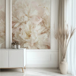 A minimalist living room showcases the Whispers of Peonies Wallpaper Mural by Decor2Go on the wall, complemented by a white sideboard with a small plant and a floor vase filled with tall pampas grass beside the sheer curtained window.