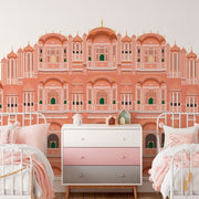 Bedroom - A children's bedroom with twin beds, both with pink bedding. The room features a large wall mural depicting a grand, ornate palace inspired by Jaipur Mahal, beautifully illustrated in red and pink from Decor2Go Wallpaper Mural.