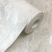 A roll of light gray, nonwoven wallpaper partially unrolled on a matching light gray textured surface. The Decoro Texuture Wallpaper (56 SqFt) by Ontario appears to have a subtle, irregular pattern giving it a slightly distressed or weathered look, perfect for creating that unique drop match effect.