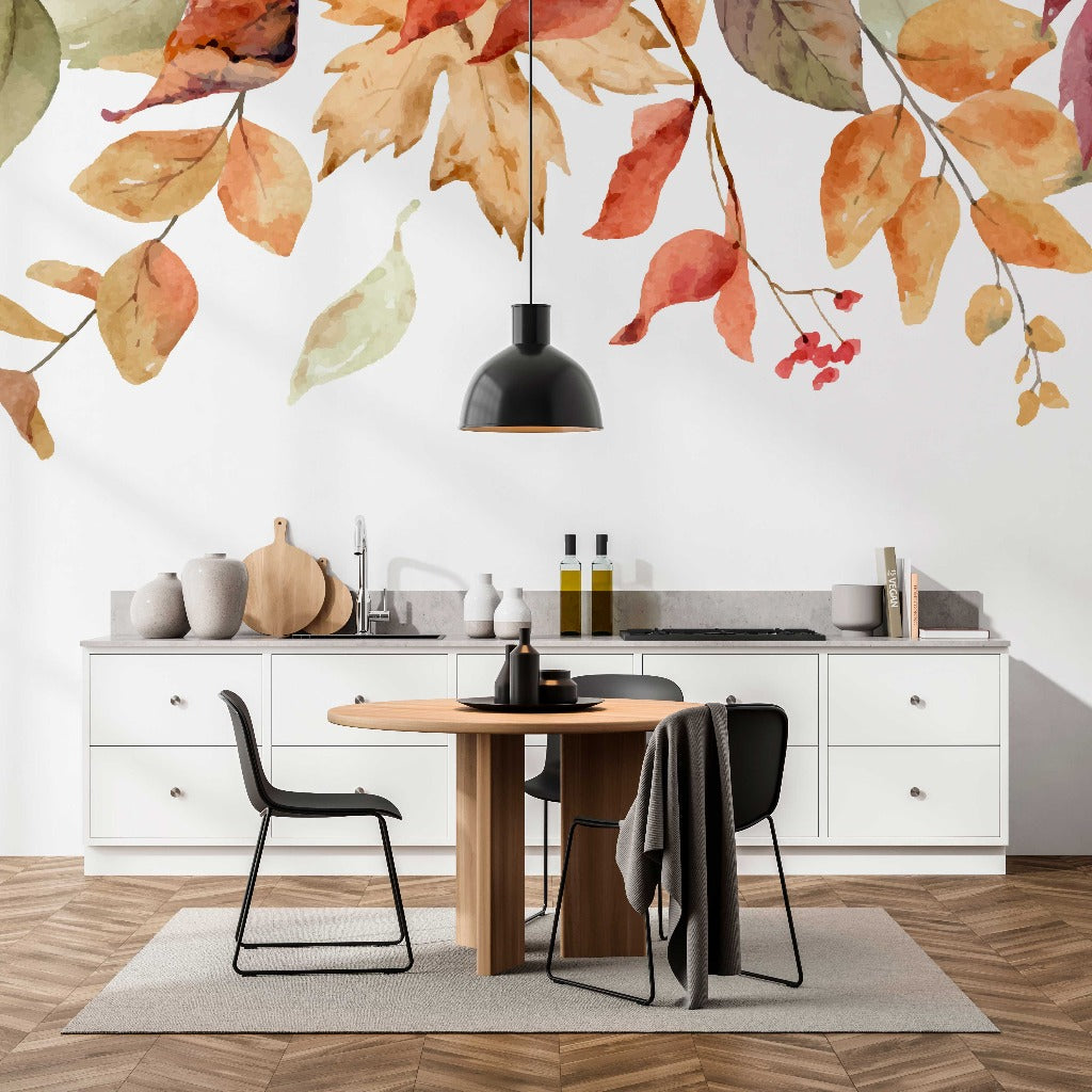 A modern kitchen with white cabinets, a round wooden table, black chairs, and custom Falling Leaves Wallpaper Murals on the wall. A black pendant light hangs above the table.