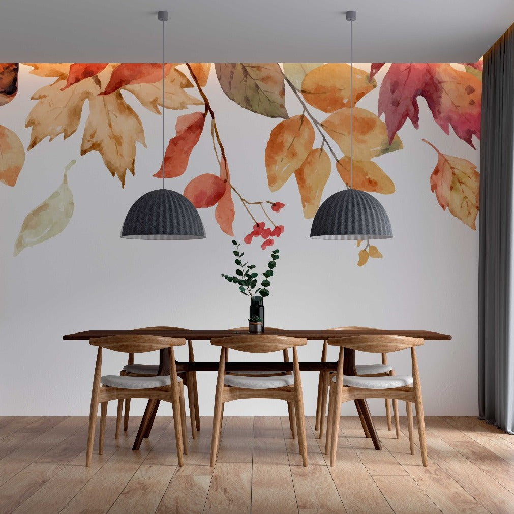 A cozy dining room featuring a wooden table with four chairs, a vase with red flowers, two dark pendant lights, and Decor2Go Falling Leaves Wallpaper Mural.