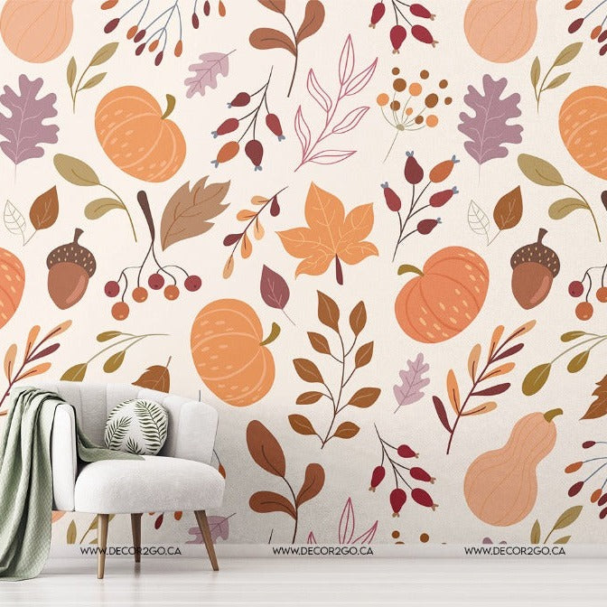 A cozy room corner with a stylish armchair and throw blanket near a decorated wall featuring a vibrant kids room Decor2Go Wallpaper Mural with leaves, branches, and pumpkins. A small plant stand with greenery is visible.