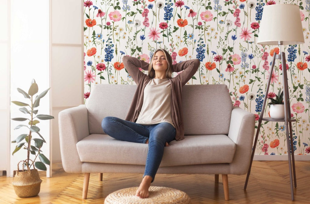 Living Room - A woman relaxing on a sofa with her arms behind her head, smiling contentedly in a cozy living room with Decor2Go Wallpaper Mural's Floral Summer Wallpaper Mural and a stylish lamp.
