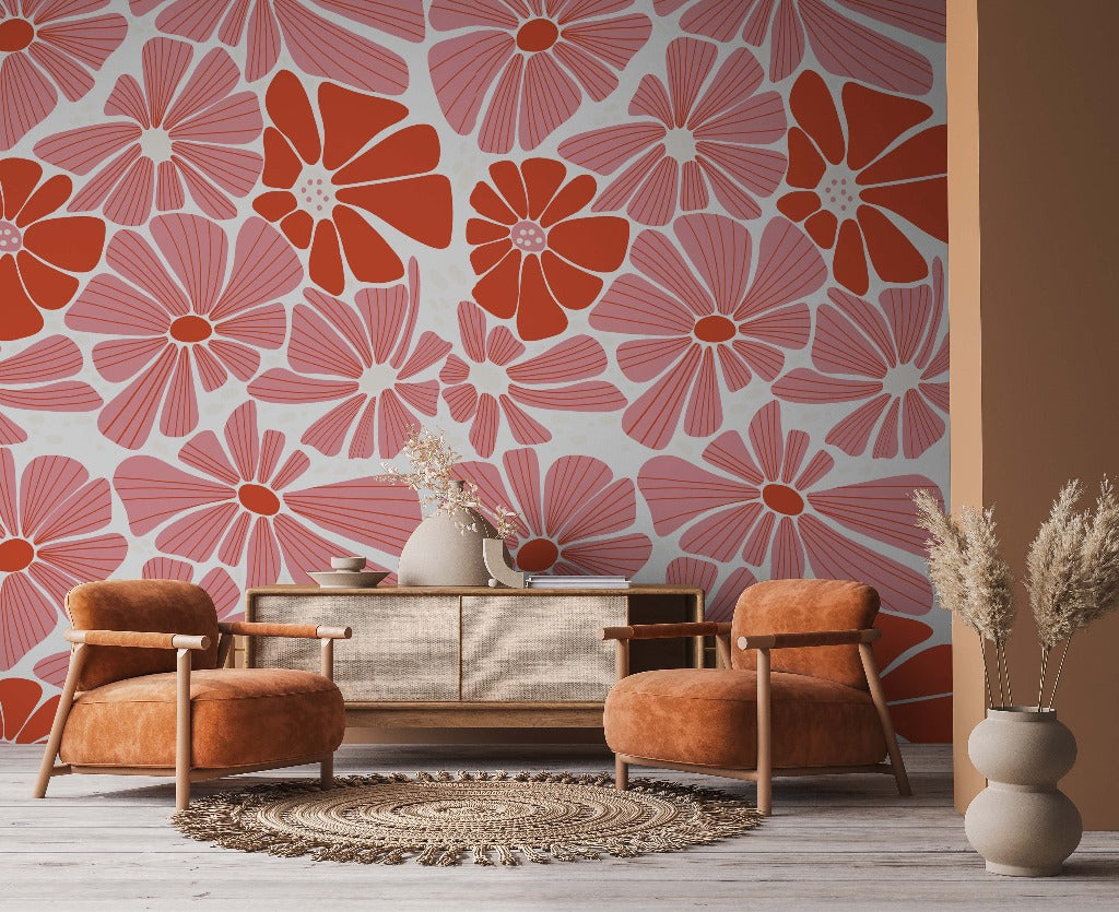 Living Room - A cozy living room corner featuring two plush orange armchairs, a beige sofa, and a circular rug. The room is accented by a bold custom mural depicting Groovy Flowers Wallpaper Mural in shades of orange and yellow.