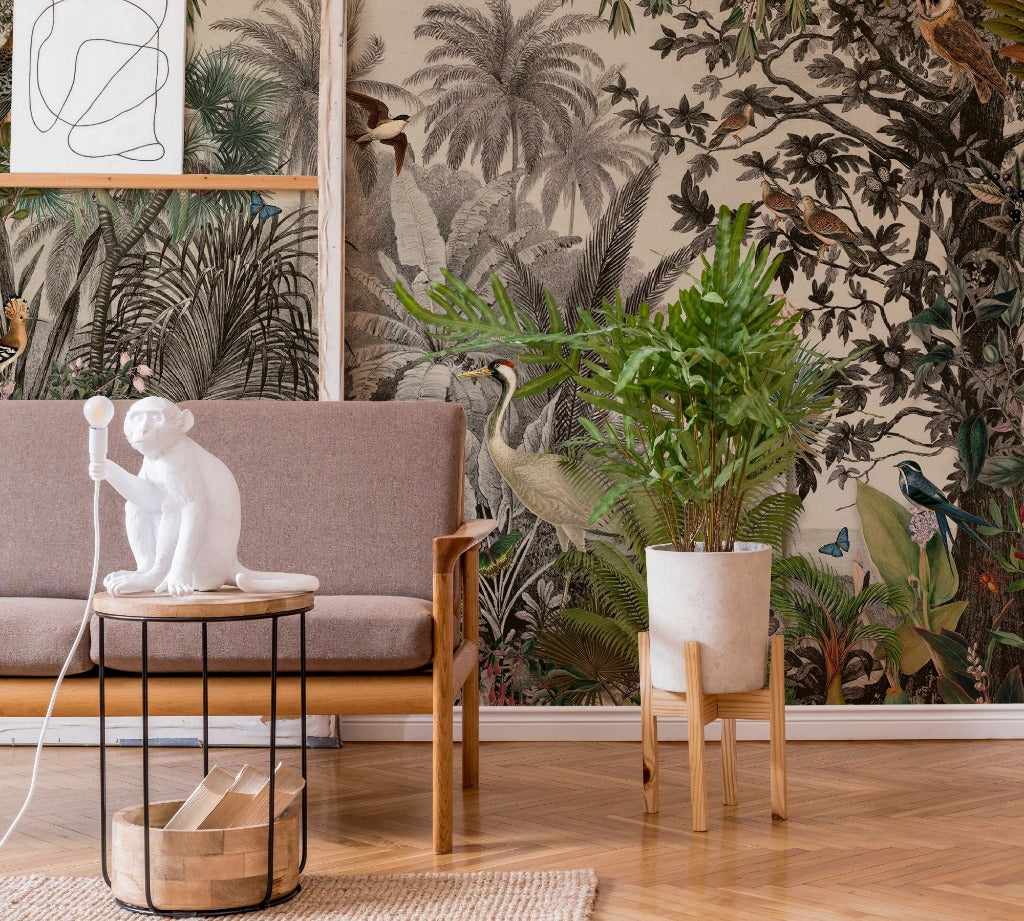 Living Room - A stylish living room corner featuring a gray sofa, a small table with a white monkey figurine lamp, a wooden chair, a tall potted plant, and a wall covered in Decor2Go Wallpaper Mural's Vintage Jungle Wallpaper Mural.