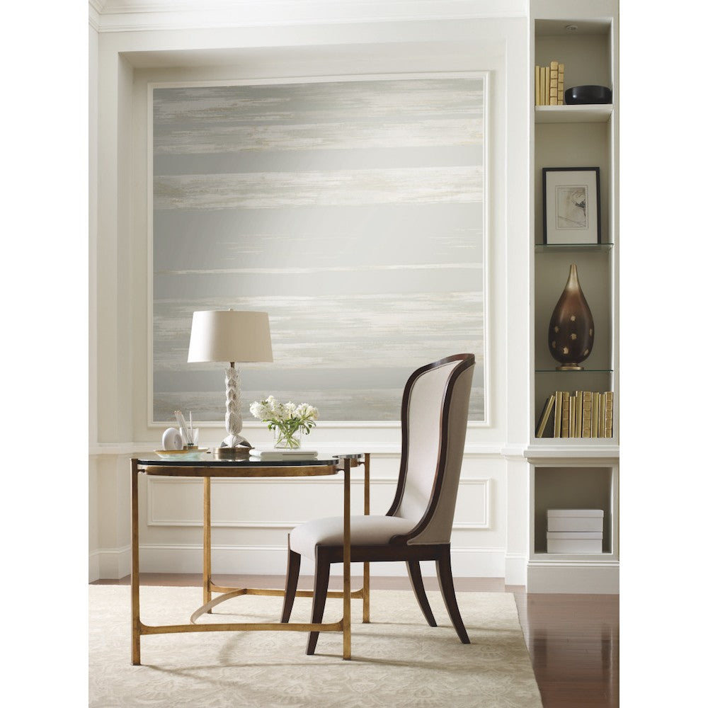 Home Office - A modern area featuring a sleek black desk with gold accents, a white upholstered chair, and a white table lamp. Dry Brush Wallpaper (60 SqFt) by York Wallcoverings with abstract wall art in grey tones adds depth behind the built-in shelves holding books and decorative items, while a vase with white flowers completes the look