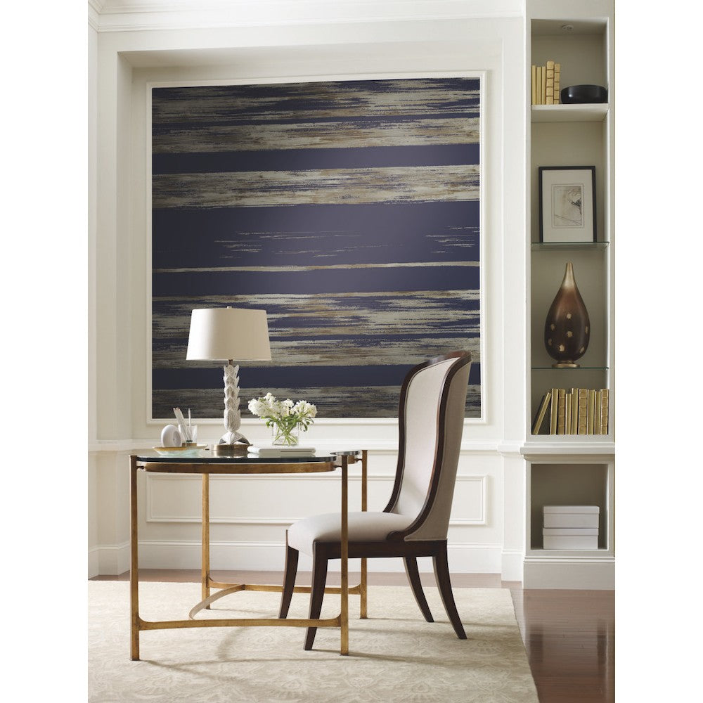 Home Office - A modern featuring a sleek glass and gold metal desk, an upholstered chair, and a white lamp with a twisted base. Behind the desk is a large abstract blue and beige painting on Horizontal Dry Brush Wallpaper (60 SqFt) from York Wallcoverings. Shelves with decor items and books are on the right wall