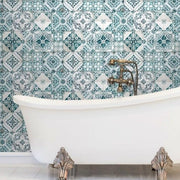 Bathroom - A white clawfoot bathtub stands against a wall adorned with intricate blue and white patterned tiles. The vintage-style brass faucet complements the bathtub's classic feet, enhanced by the use of York Wallcoverings' Mediterranean Tile Wallpaper, creating a luxurious and timeless setting
