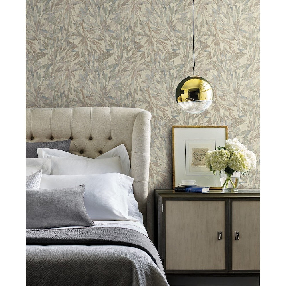 Bedroom - A scene featuring a beige, tufted headboard and a neatly made bed with white and grey pillows and bedding. A nightstand with framed art, a book, and a vase of white flowers sits beside the bed. A brass pendant light hangs from the ceiling, with Rainforest Leaves Wallpaper (56 SqFt) by York Wallcoverings creating a tropical canopy backdrop